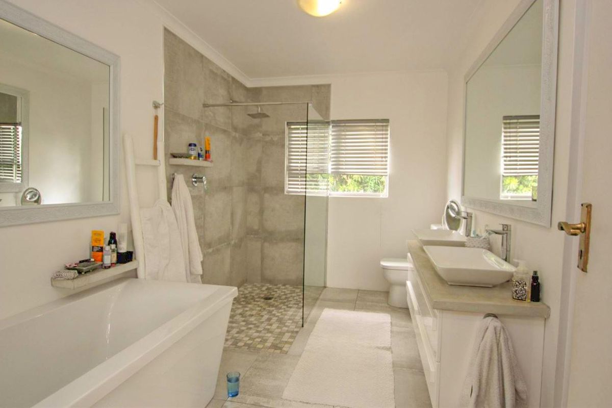 Modern bathroom featuring a double vanity with vessel sinks, a freestanding bathtub, and a spacious walk-in shower with glass enclosure.