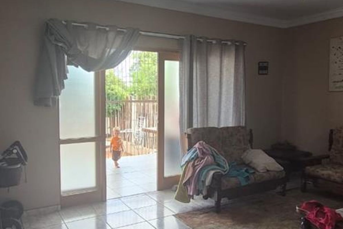 A living room featuring tiled flooring, a ceiling fan, and glass sliding doors providing direct access to an outdoor patio area.