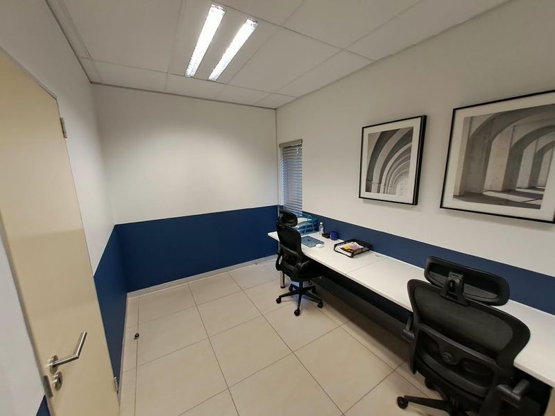 A professional office space featuring a built-in desk, tiled flooring, and recessed lighting, providing a clean and functional work environment.