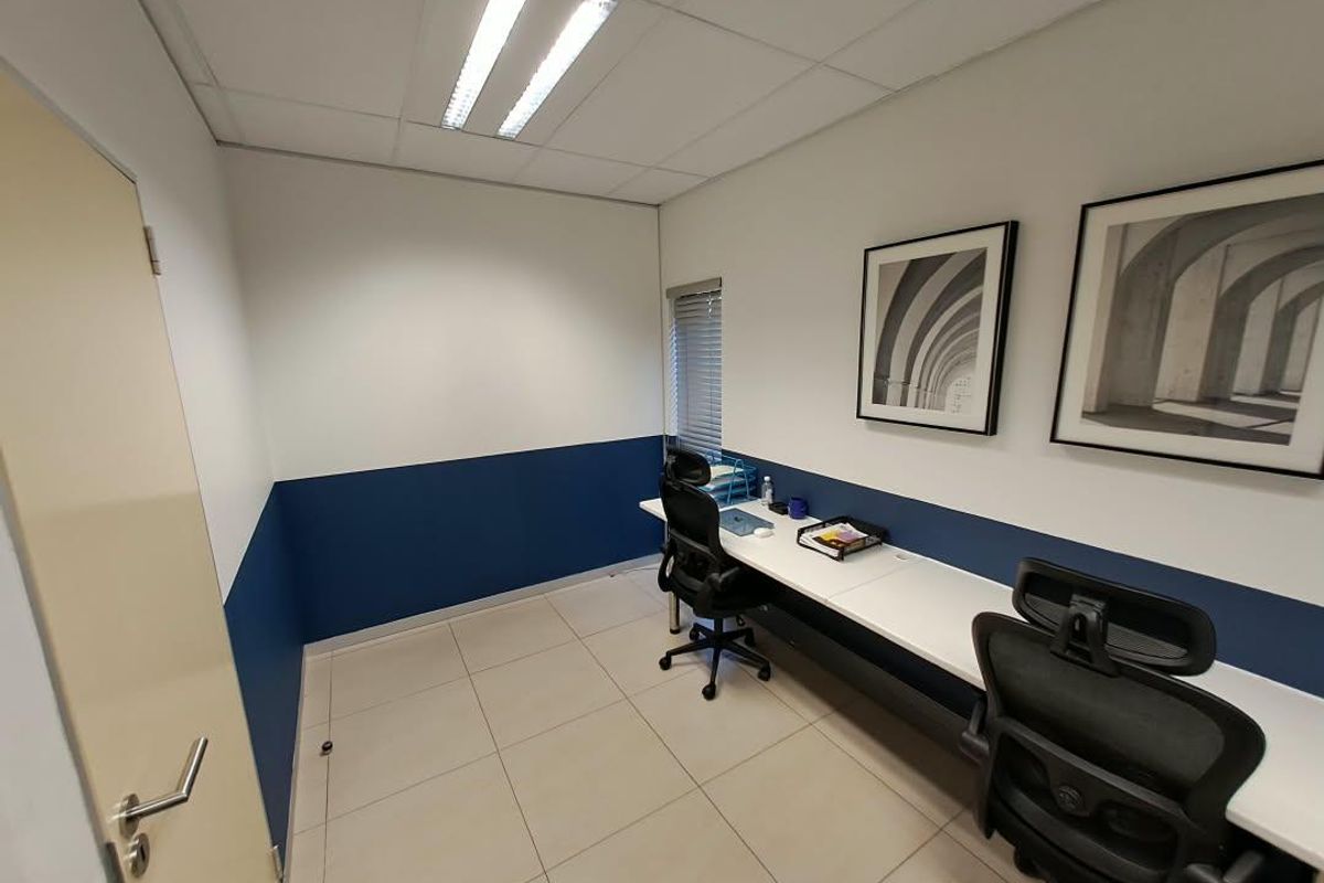 A professional office space featuring a built-in desk, tiled flooring, and recessed lighting, providing a clean and functional work environment.