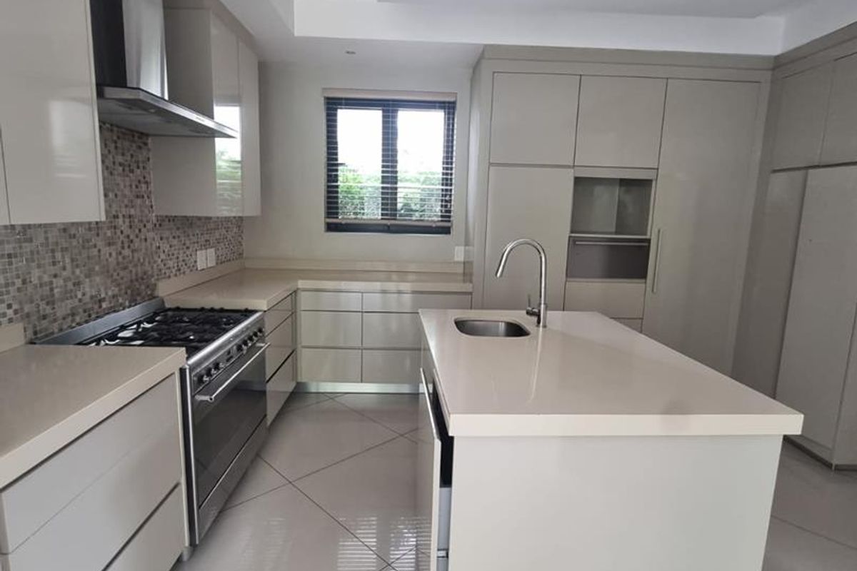 Modern kitchen featuring sleek cabinetry, stone countertops, a central island with a sink, and high-quality stainless steel appliances.