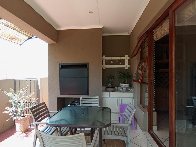Covered patio area featuring a built-in braai, tiled flooring, and direct access to the interior through sliding doors.
