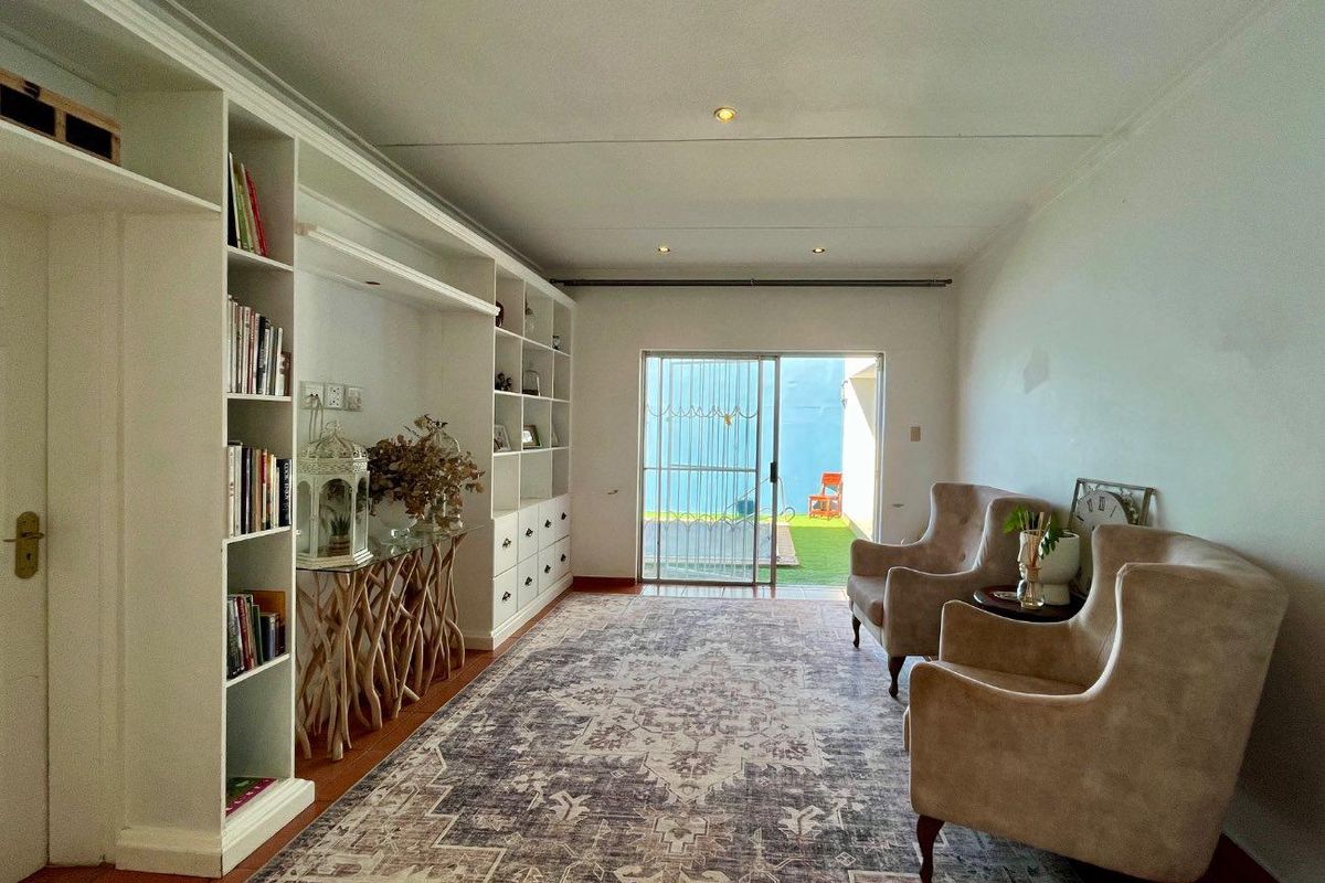 A living room featuring built-in floor-to-ceiling shelving and sliding glass doors that provide direct access to an outdoor patio area.