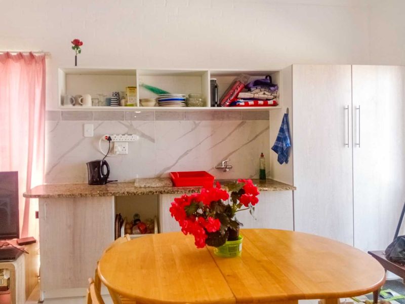 A compact kitchen area featuring granite countertops, marble-look tile backsplash, built-in cabinetry, and open shelving for storage.