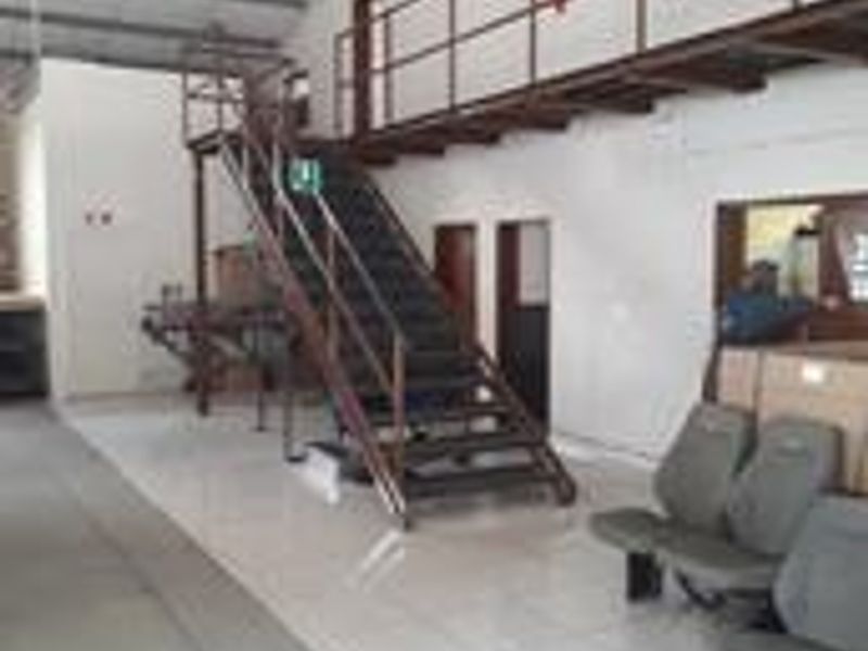 Industrial utility space featuring a metal staircase leading to a mezzanine level with tiled flooring and exposed structural elements.
