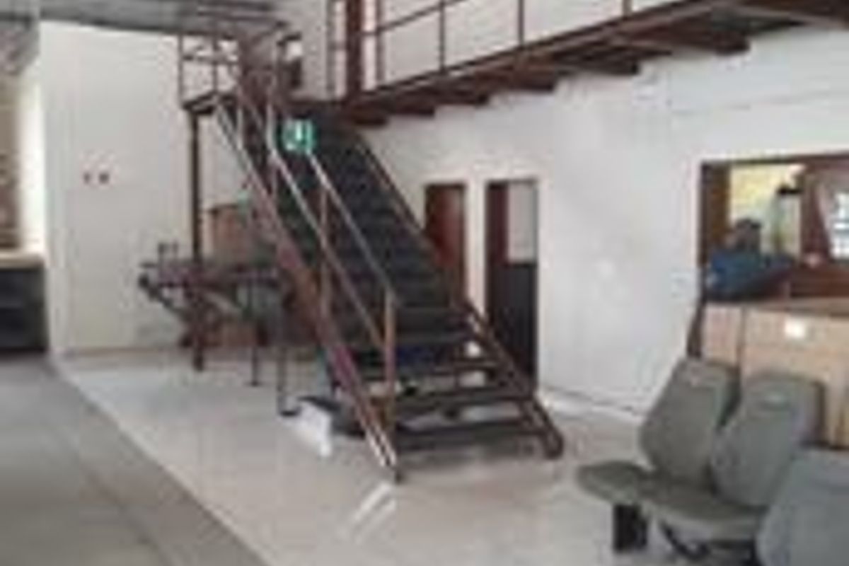 Industrial utility space featuring a metal staircase leading to a mezzanine level with tiled flooring and exposed structural elements.