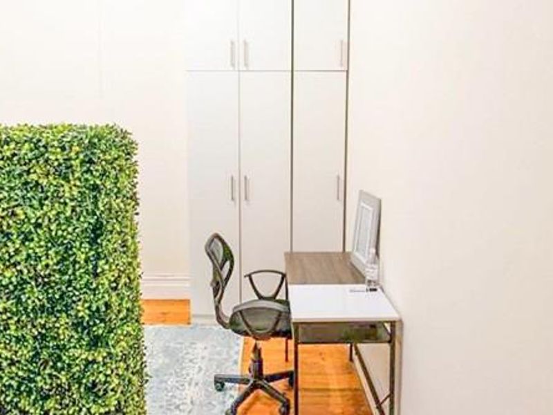 A functional home office space featuring built-in white cabinetry and warm hardwood flooring, providing a clean and organized work environment.