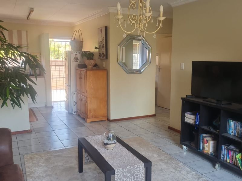 Open plan living area featuring ceramic floor tiles and coved ceiling cornices, with direct access to an exterior security gate.