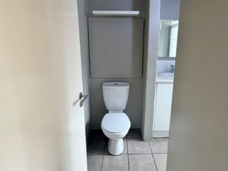 A functional bathroom featuring tiled flooring, a standard toilet, and a vanity unit with a mirror.