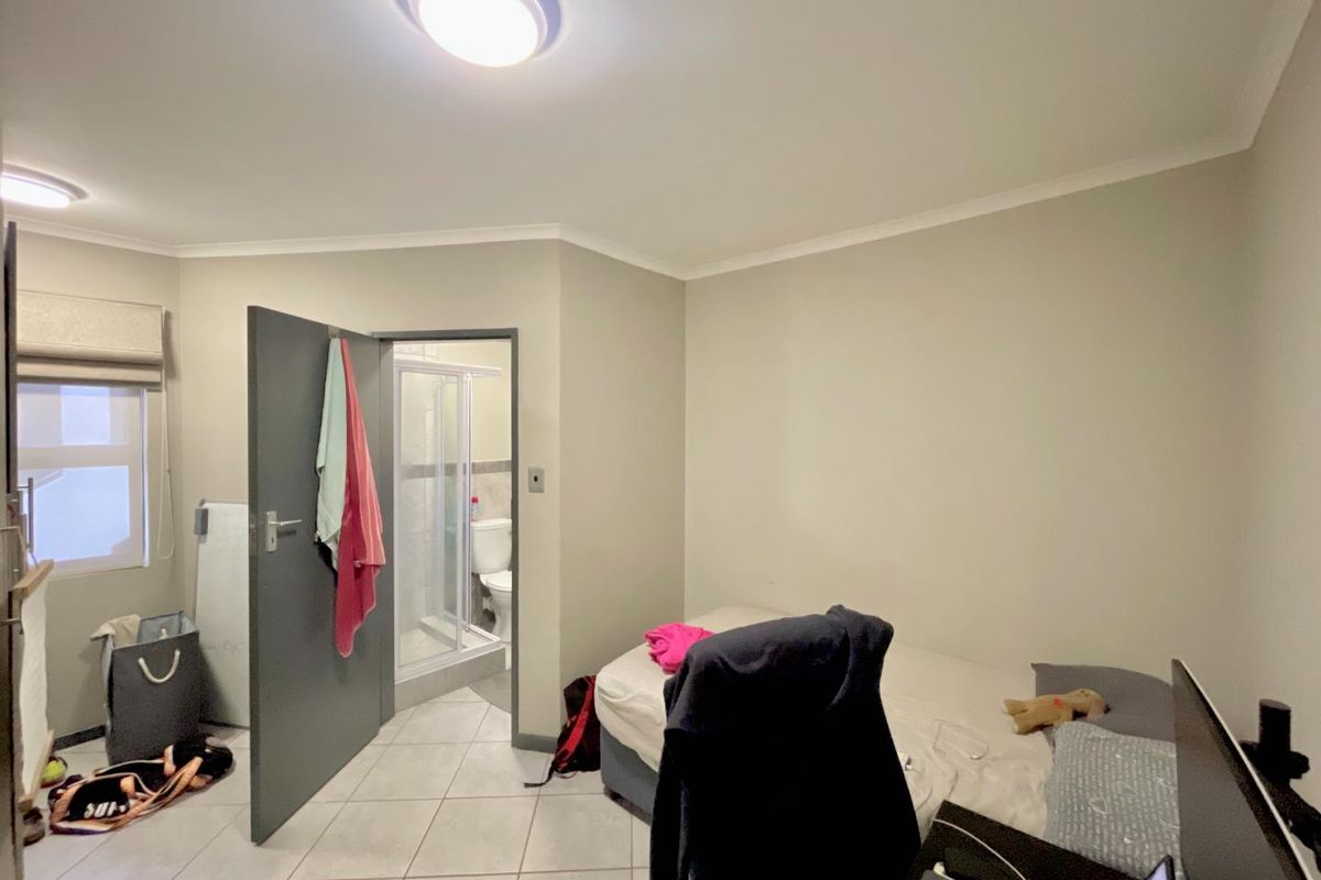 A bedroom featuring tiled flooring, a neutral color palette, and an en-suite bathroom with a shower enclosure.