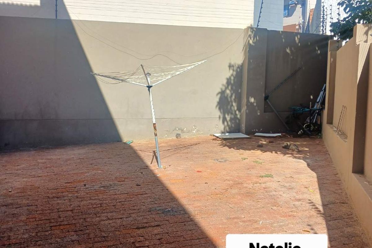 A private rear courtyard area featuring brick paving and high boundary walls with security fencing.