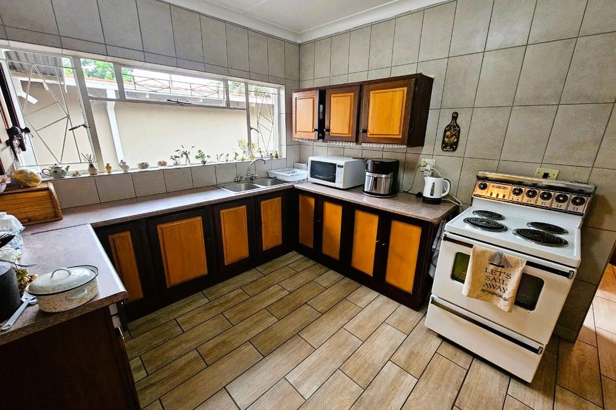 A functional kitchen featuring wood-toned cabinetry, tiled splashbacks, tiled flooring, and a freestanding electric stove.