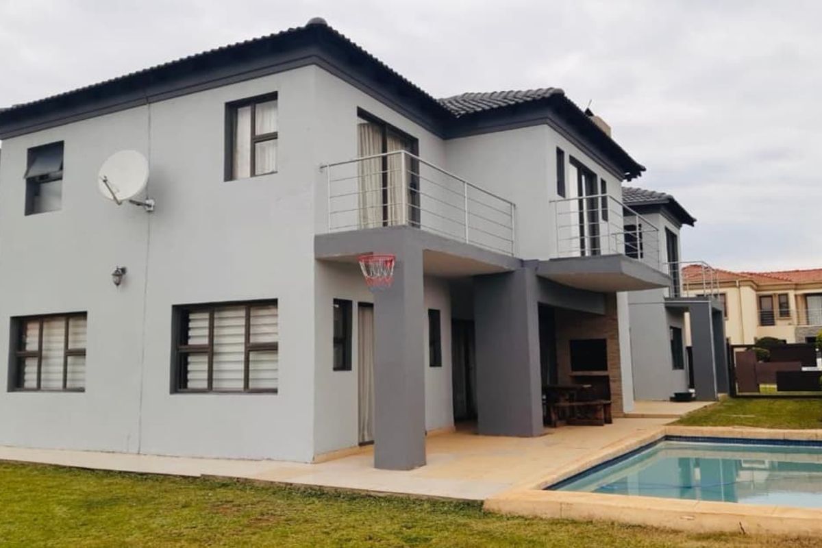 Rear view of a two-story townhouse featuring a swimming pool, covered patio area, and upper-level balconies with metal railings.