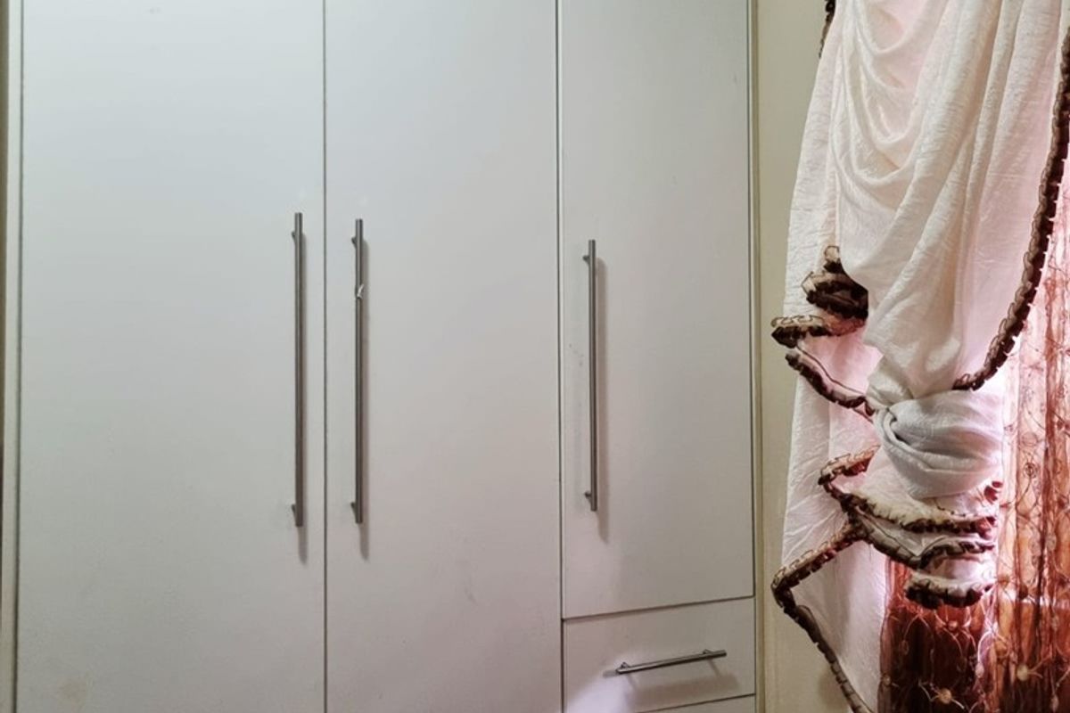 A bedroom featuring white built-in cupboards with integrated drawer storage and modern metal handles.