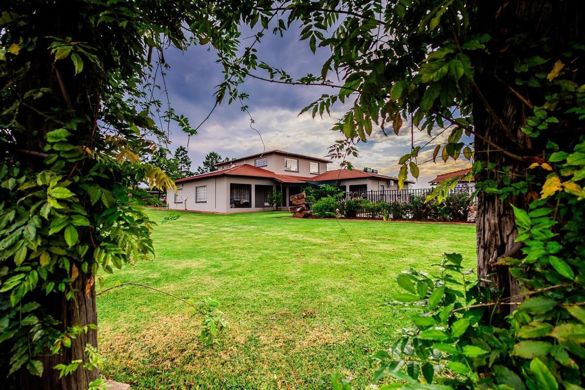 A view of the rear elevation of the house, featuring a spacious lawn and landscaped garden area.