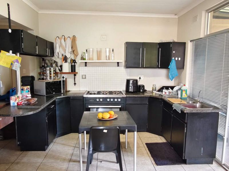 A functional kitchen featuring dark cabinetry, a gas hob, oven, and tiled flooring, with direct access to an outdoor patio area.