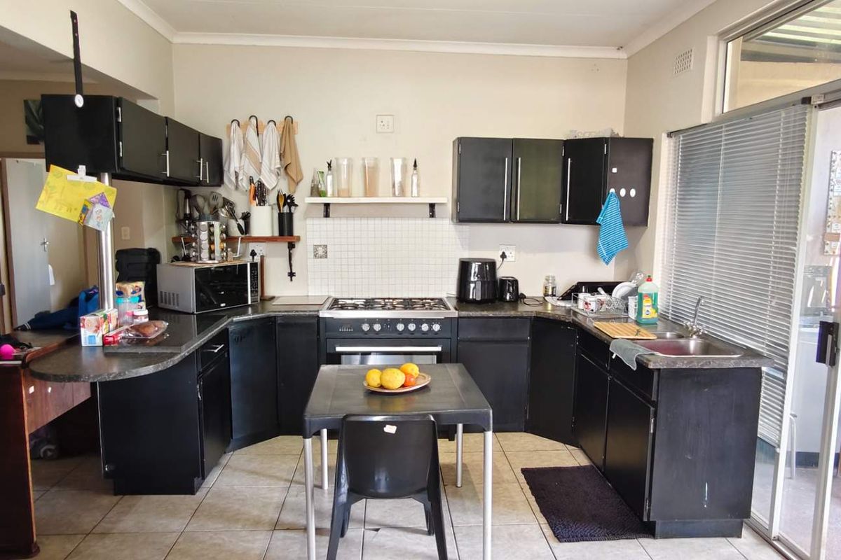A functional kitchen featuring dark cabinetry, a gas hob, oven, and tiled flooring, with direct access to an outdoor patio area.