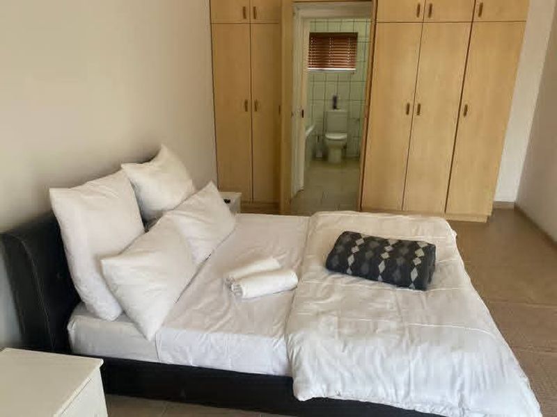 Bedroom featuring built-in wooden cupboards and direct access to an en-suite bathroom.