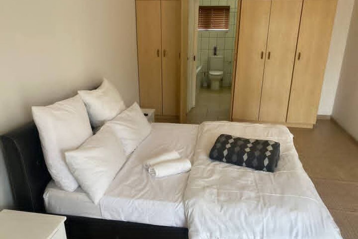 Bedroom featuring built-in wooden cupboards and direct access to an en-suite bathroom.
