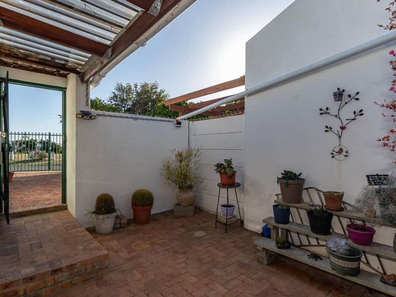 A covered outdoor patio area featuring brick paving, timber rafters, and a corrugated roof, providing a functional space for outdoor relaxation.