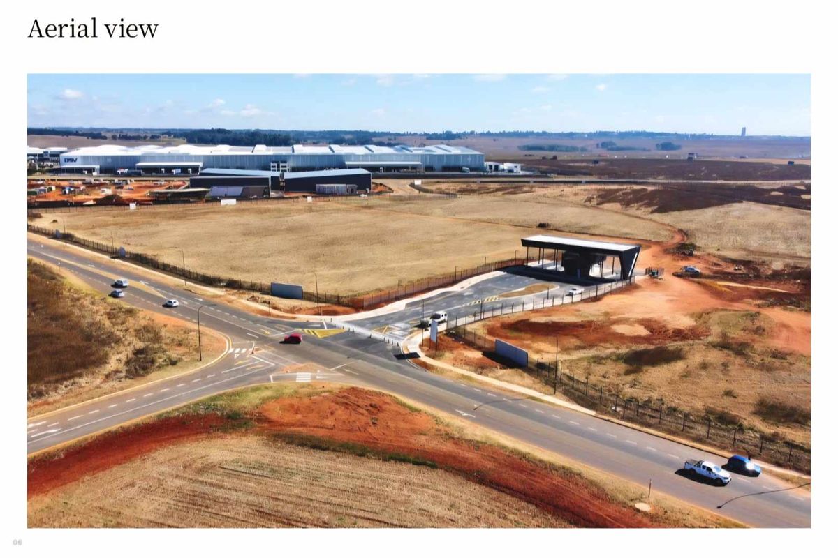 Aerial view of the industrial property site, featuring a secure gated entrance, paved access roads, and expansive surrounding land.