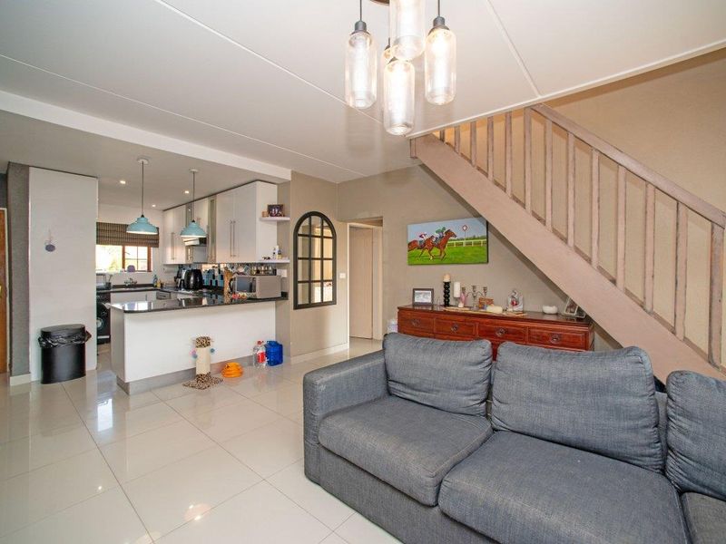Open-plan living area featuring a modern kitchen with granite countertops, tiled flooring, and a staircase leading to the upper level.