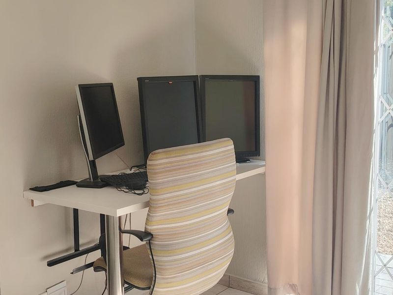 A functional home office space featuring a wall-mounted desk and access to an outdoor area through a security gate.