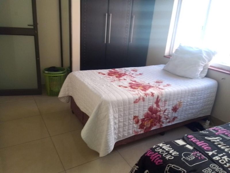 A functional bedroom featuring tiled flooring and a built-in wardrobe, providing essential storage space.