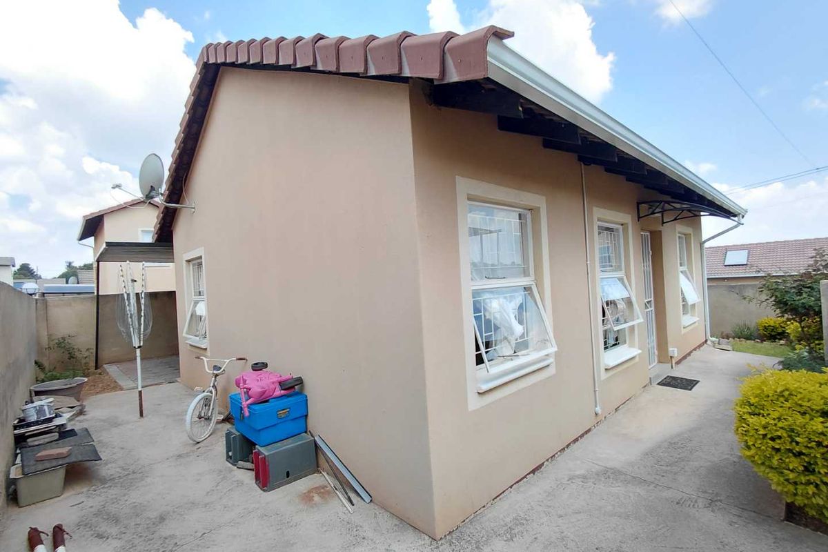 Side view of the house showing the exterior wall, tiled roof, and concrete pathway surrounding the property.