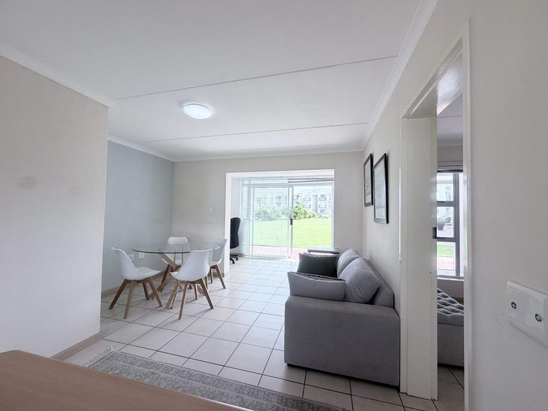 An open-plan living and dining area featuring tiled flooring and a sliding glass door providing access to the exterior.