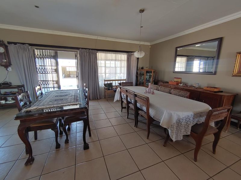 Spacious dining room featuring tiled flooring, coved cornicing, and a large sliding glass door providing access to the exterior.