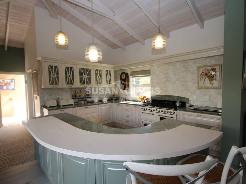 Spacious kitchen featuring a large curved breakfast bar, vaulted ceilings, and classic cabinetry with a built-in gas range stove.
