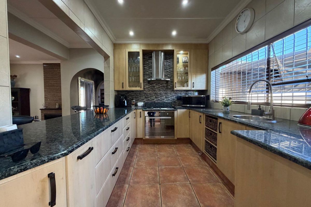 A well-appointed kitchen featuring granite countertops, built-in cabinetry, stainless steel appliances, and a tiled backsplash, offering a functional and classic cooking space.