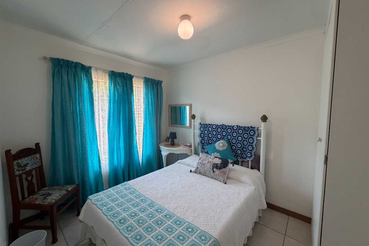A standard bedroom featuring tiled flooring, built-in cupboard space, and a window with curtain fixtures.