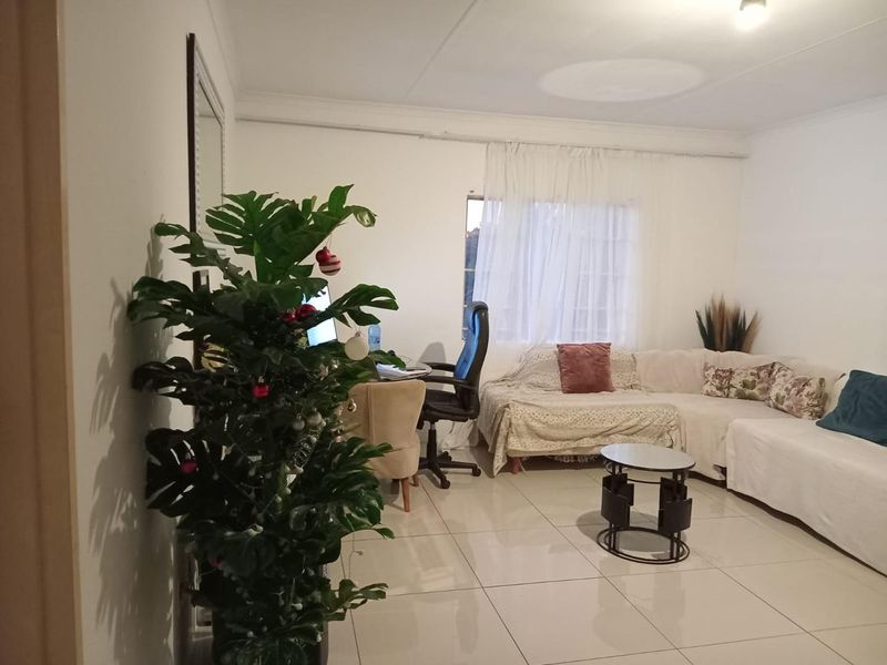 A living room featuring neutral tiled flooring and a coved ceiling, providing a functional and well-lit space for relaxation.