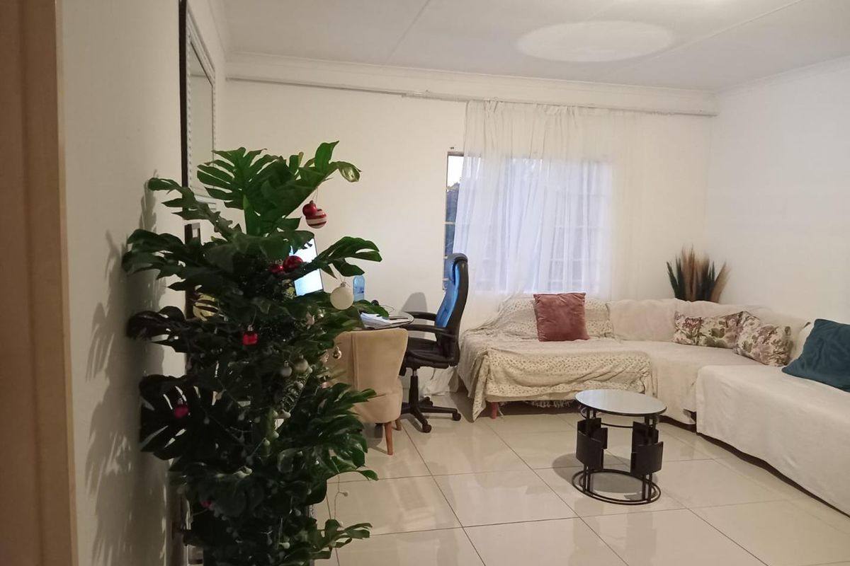 A living room featuring neutral tiled flooring and a coved ceiling, providing a functional and well-lit space for relaxation.