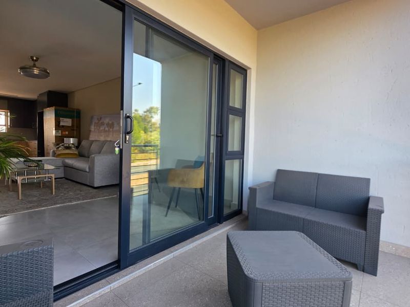 A covered balcony featuring tiled flooring, a metal balustrade, and large sliding glass doors providing seamless access to the interior living area.