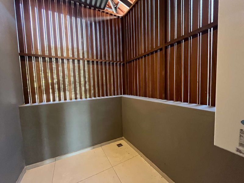 A private outdoor balcony area featuring modern tiled flooring and a decorative timber slat privacy screen.