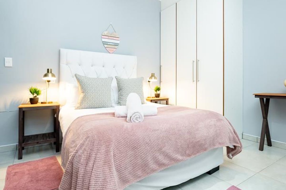 A well-maintained bedroom featuring light-toned tiled flooring, a built-in wardrobe with white cabinetry, and neutral wall finishes.