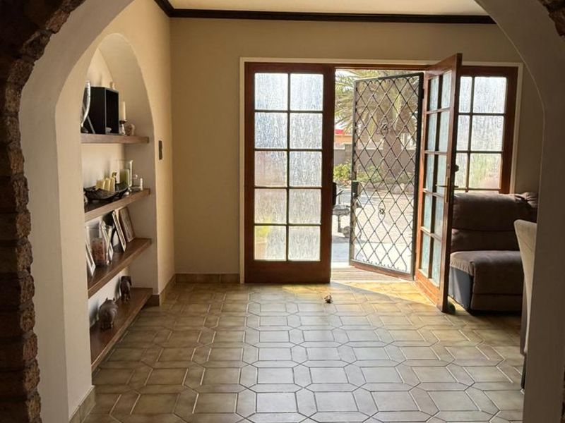 Entrance area featuring a rustic brick archway, tiled flooring, and built-in shelving, leading through french doors to the exterior.