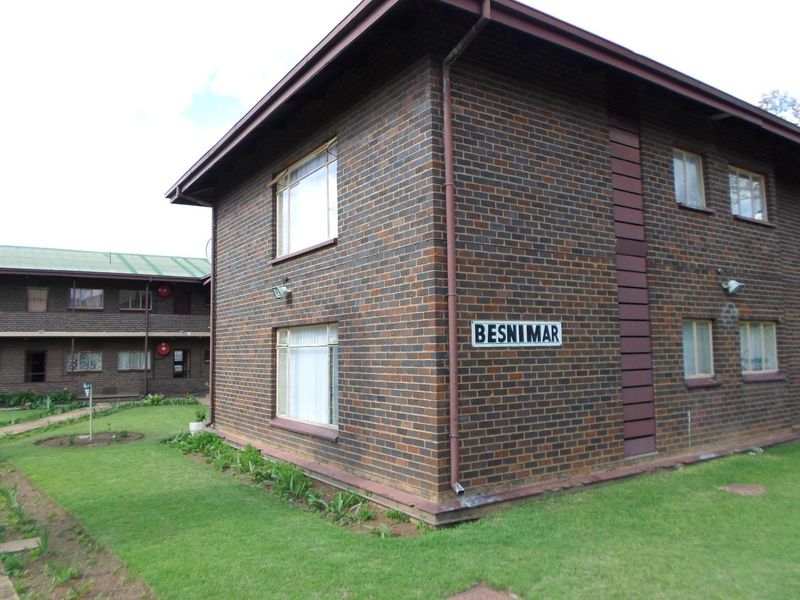Exterior view of the Besnimar apartment complex featuring a face brick facade, established lawn, and functional external lighting.