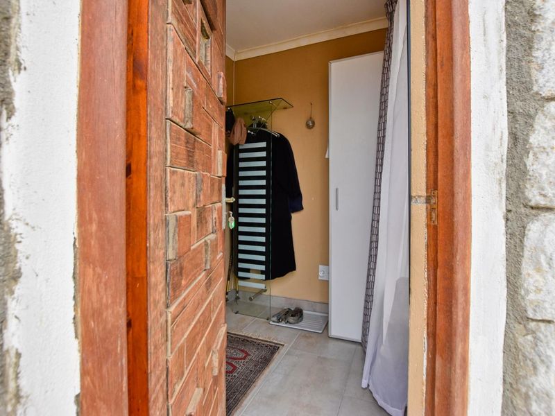 A small entryway featuring a rustic wooden door, tiled flooring, and a built-in storage cupboard.