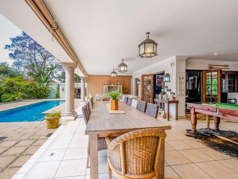 Spacious covered patio featuring tiled flooring, classic columns, and direct access to a swimming pool, ideal for outdoor entertaining.