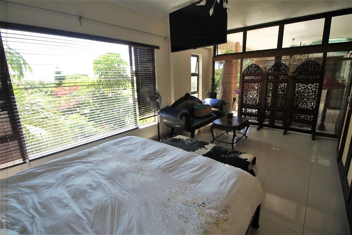 Spacious bedroom featuring large windows with venetian blinds, tiled flooring, and glass sliding doors leading to an outdoor area.