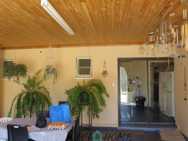 A covered patio area featuring a timber-clad ceiling, tiled flooring, and sliding glass doors providing access to the interior living space.