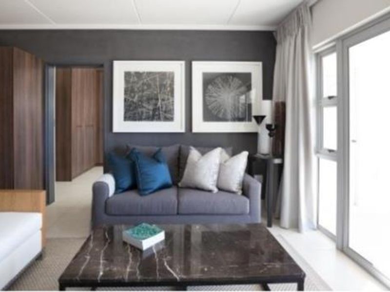 A modern living room featuring a dark accent wall, built-in storage, and large sliding glass doors providing natural light.