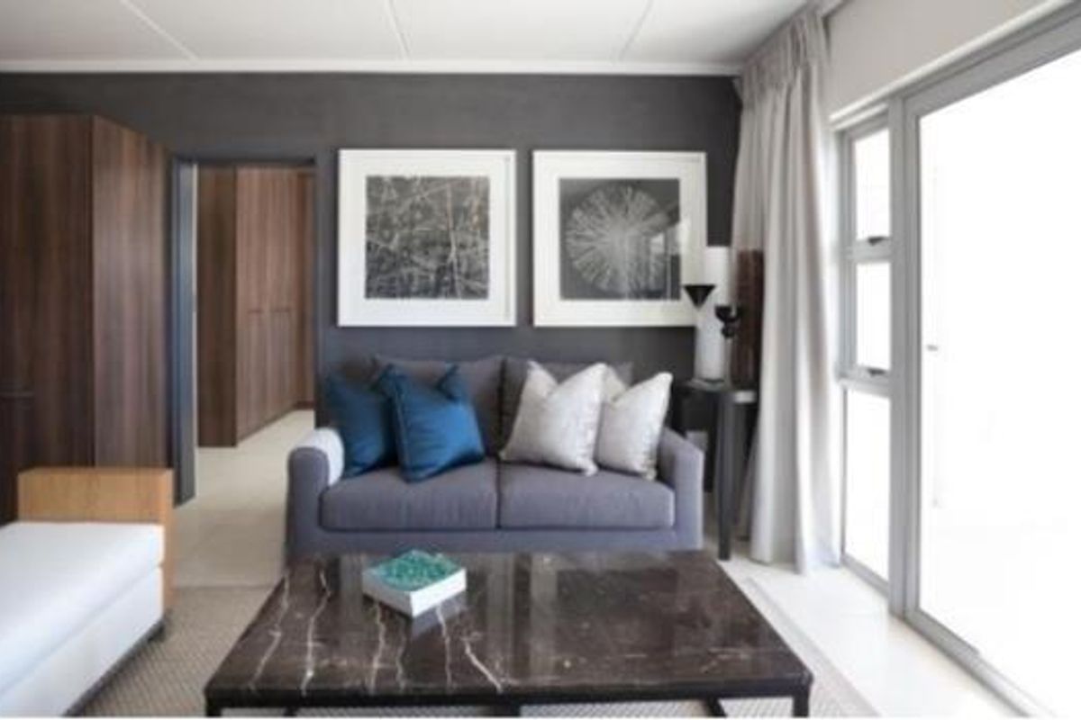 A modern living room featuring a dark accent wall, built-in storage, and large sliding glass doors providing natural light.
