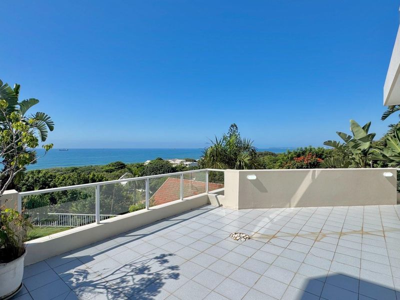 Spacious balcony featuring tiled flooring, a modern glass balustrade, and expansive ocean views, providing an ideal outdoor entertainment space.
