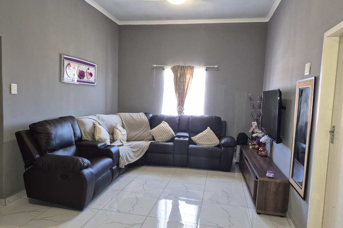 A living room featuring polished tiled flooring, neutral grey walls, and a central ceiling light fixture.