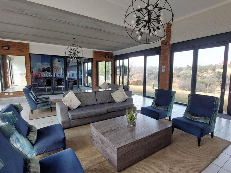Spacious living area featuring exposed brick accents, large sliding glass doors providing natural light, and modern pendant lighting with scenic outdoor views.